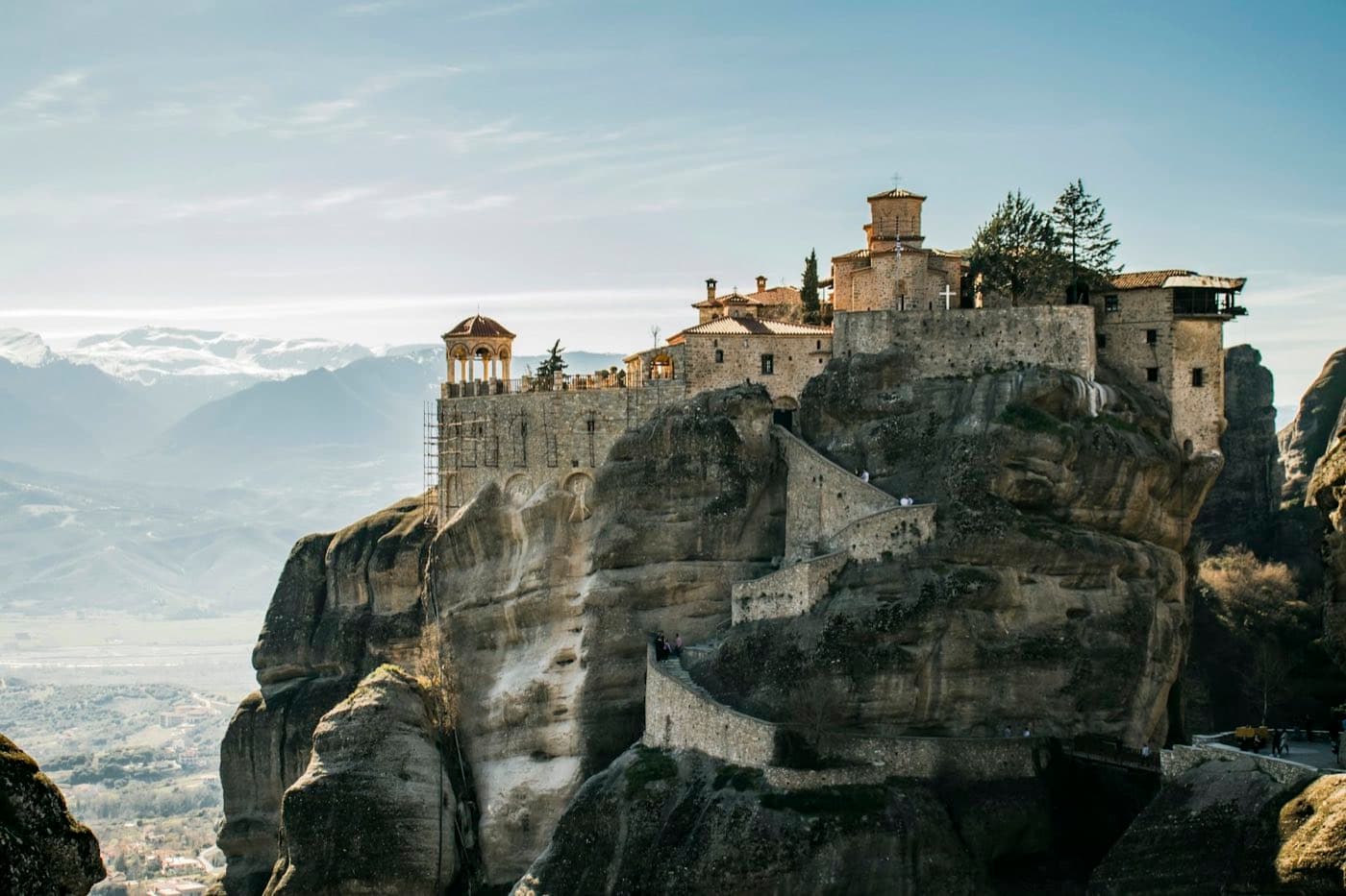 Le monastère de Varlaam perché au sommet de son piton de grès aux Météores, montagnes enneigées du Pinde en arrière-plan