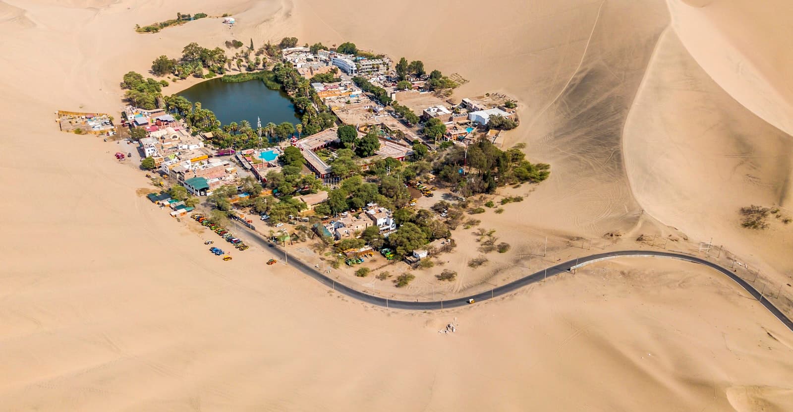 Aerial view of the Huacachina oasis, lagoon and palm trees ringed by the giant dunes of the Ica desert