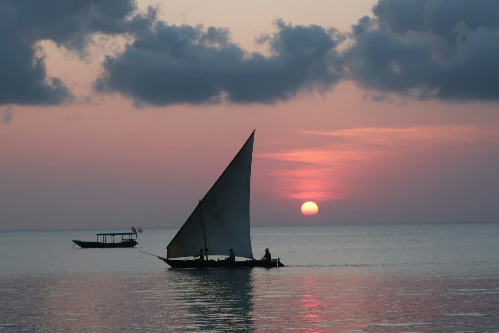 A traditional dhow with a triangular sail at sunset on the Indian Ocean, off Zanzibar